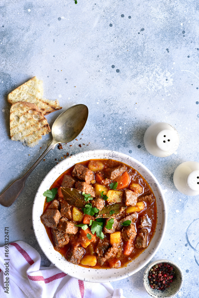 Fototapeta premium Goulash (meat stew with tomatoes and paprika) - traditional dish of hungarian cuisine .Top view with copy space.