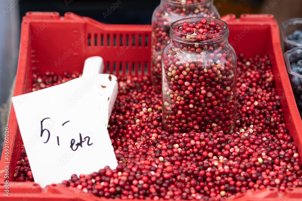 Φωτογραφία Fresh red berries displayed in a red plastic crate at an outdoor market, with so