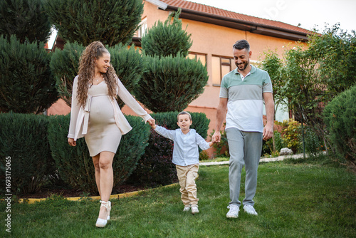 Foto Expecting family enjoys a joyful stroll in green garden