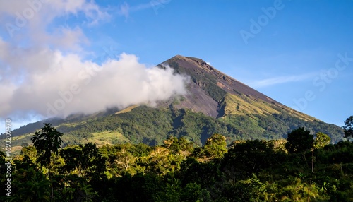 Volcanic peak shrouded in clouds, lush forest base