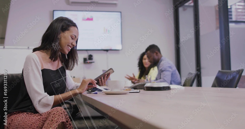 Fototapeta premium Smiling early career worker using tablet in conference room, with coffee cup, screen, copy space