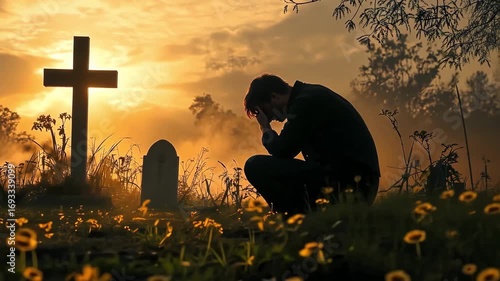 Mourning man at a grave with cross at sunset, expressing grief and loss.