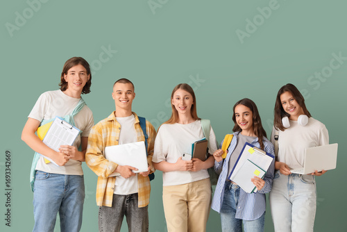 Group of students with laptops and notebooks on green background