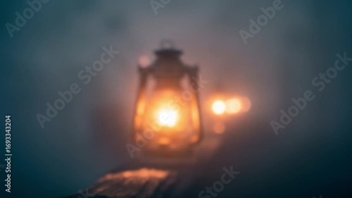 Blurred image of a lit vintage oil lantern possibly held by someone in foggy surroundings