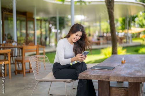 Smiling businesswoman using smartphone in outdoor cafe, enjoying break time