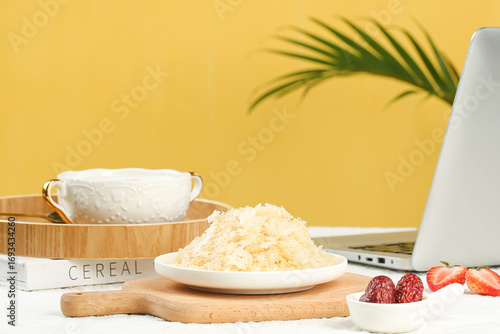 Healthy breakfast setup with golden instant cereal and silver ear fungus on wooden cutting board with laptop workspace