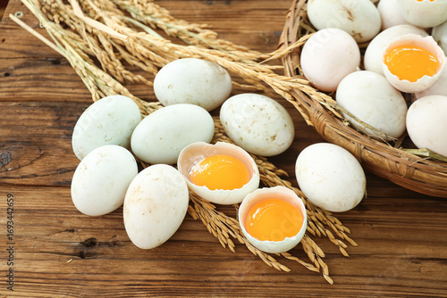Fresh Raw Duck Eggs with Orange Yolks in Wicker Basket on Wooden Background