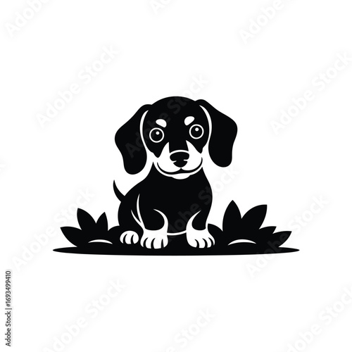 Cute black silhouette of a dachshund puppy sitting in grass