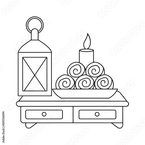 Lantern and rolled towels on a dresser with a lit candle light