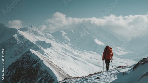 Mountaineer standing triumphantly on the summit of a majestic mountain overlooking a stunning landscape of snowy peaks and rugged alpine terrain under a clear blue sky, capturing the spirit of adventu