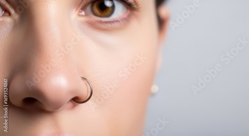 Close-up of a woman's face with a gold nose ring and a captivating brown eye