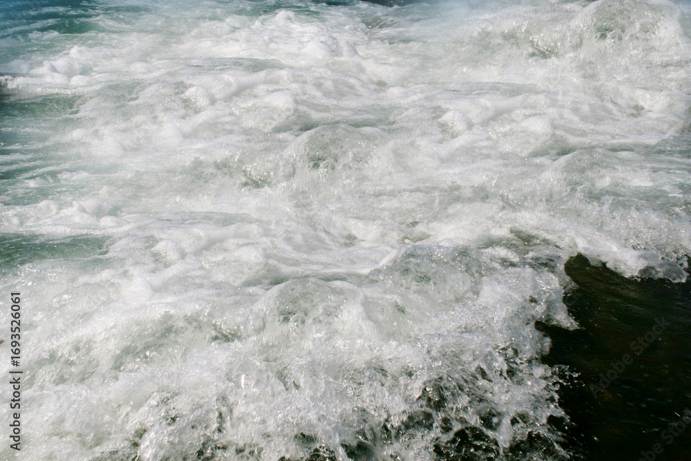 Obraz premium Foaming sea wave on a rocky shore.