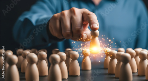 Hand selecting a glowing wooden figure from a crowd signifying talent, leadership, and success