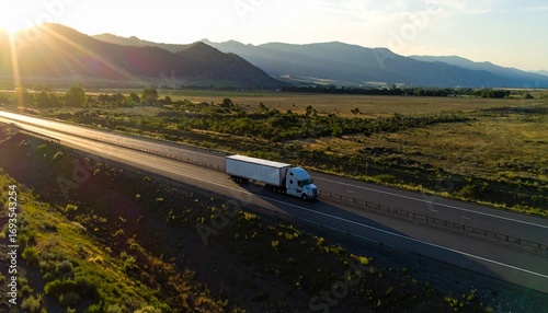 Top angle cinematic view of an 18-wheeler truck passing alone on the highway, camera panning forward from bottom right corner, dramatic lighting, motion, and realistic road perspective