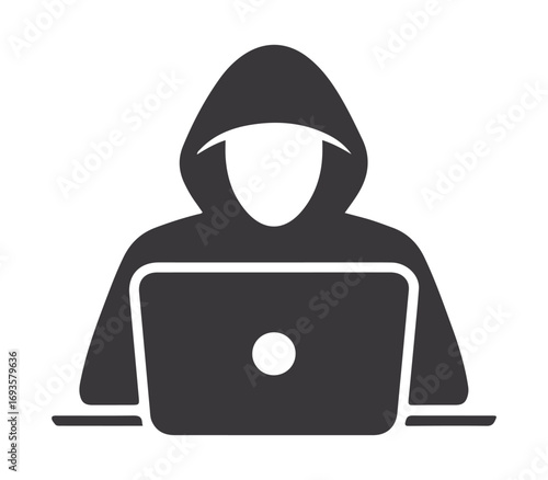 Anonymous hooded figure using a laptop computer for cybercrime and online security threats