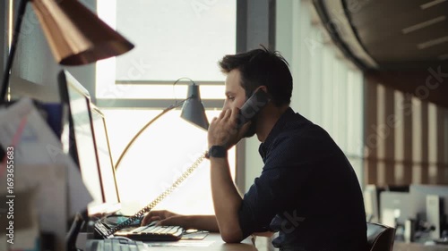 Focused businessman talking on landline phone at office desk