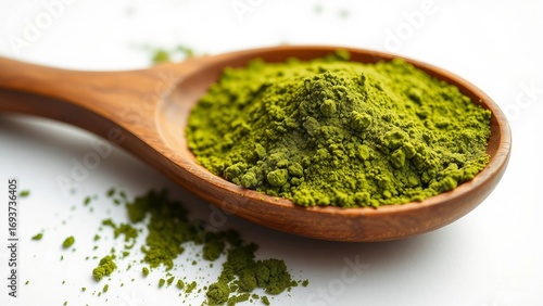 Close-up of a wooden spoon filled with vibrant green matcha powder, showcasing its fine texture and rich color against a clean white background