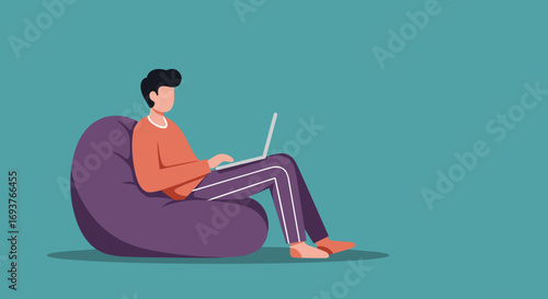 Young man comfortably working or studying on his laptop from a bean bag chair at home, illustrating remote work, online education, or casual leisure with technology.