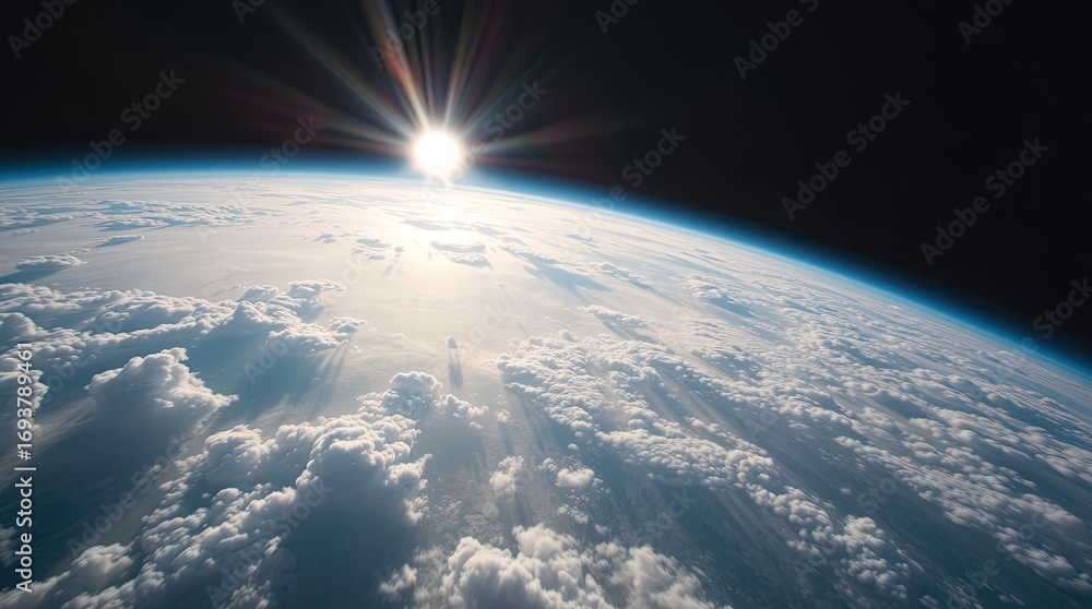 Fototapeta premium A view of Earth from space, showcasing clouds and the curvature of the planet. The sun rises on the horizon, casting rays of light across the atmosphere.