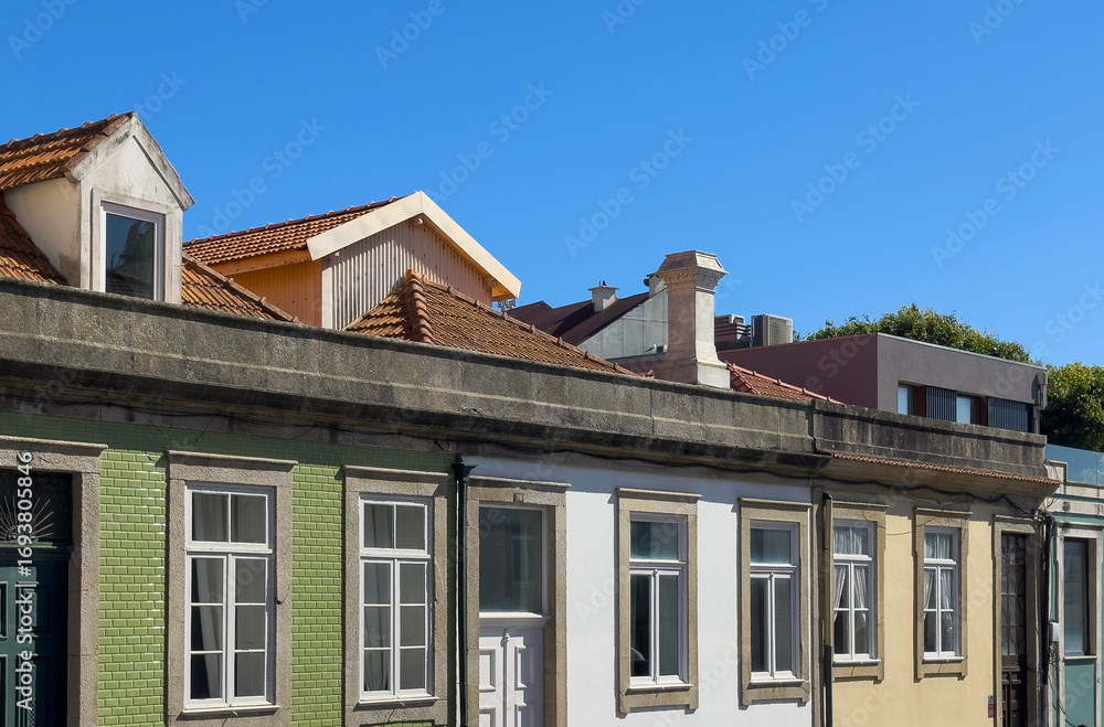 Fototapeta premium Row of traditional European houses with tiled and painted facades, old roof tiles, and chimneys,