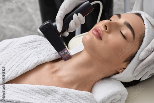 Tapeta Radiofrequency skin lifting of beautiful patient in beauty salon to improve elasticity and tightening of her neck skin
