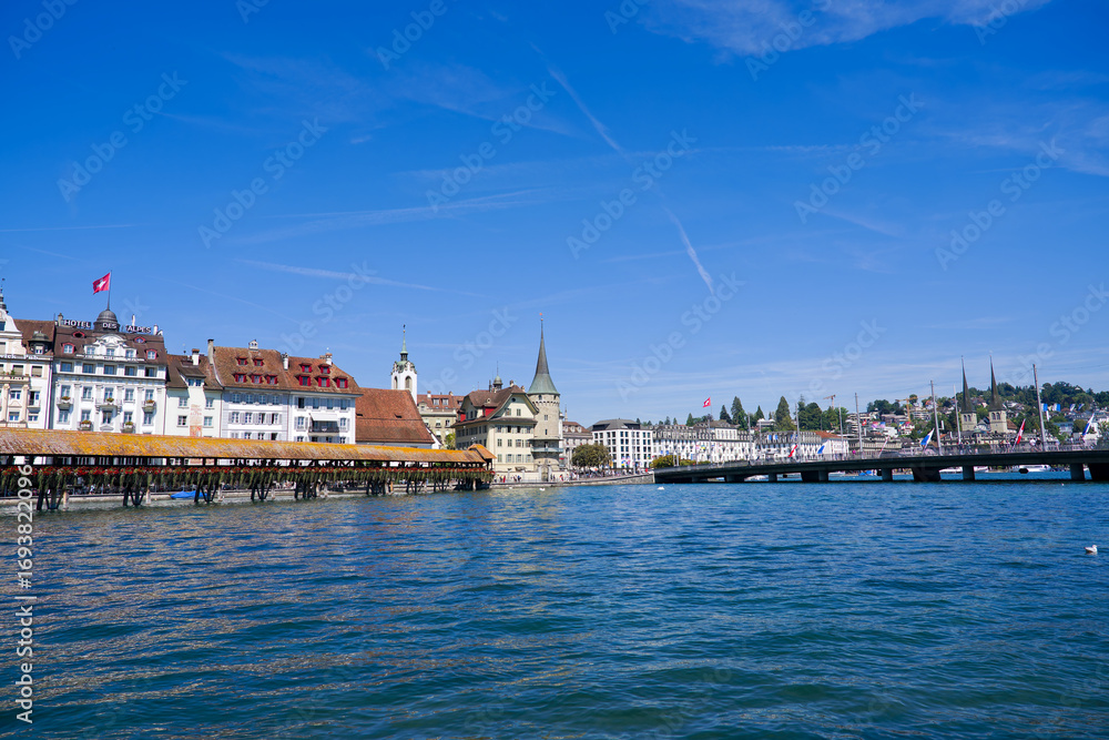 Obraz premium Scenic view of famous Chapel Bridge with Reuss River and bridge named Seebrücke at the old town of Swiss city of Luzern on a sunny summer day. Photo taken August 25th, 2025, Lucerne, Switzerland.