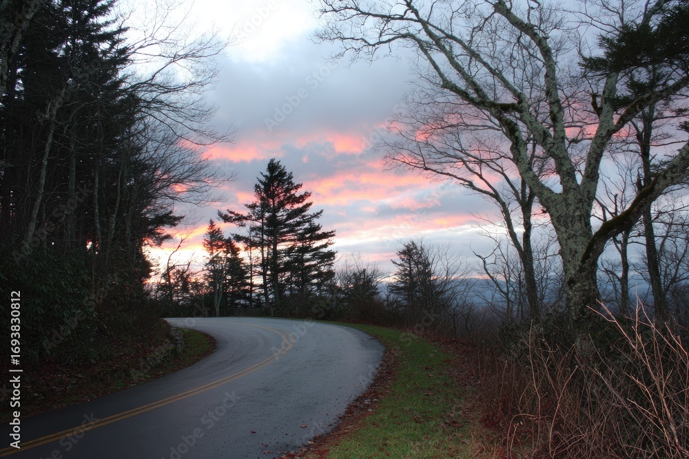 Obraz premium Winding mountain road at sunset, colorful clouds