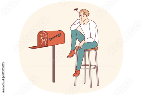 Lonely man waiting for letter, sitting by empty mailbox covered with cobwebs, wanting to receive messages from girlfriend. Lonely guy needs communication and suffers due to lack of friends