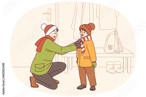 Caring father helps kid put on winter clothes so as not to freeze while walking along cold street. Happy father tying scarf to child showing care and desire to help smiling pre-teen son