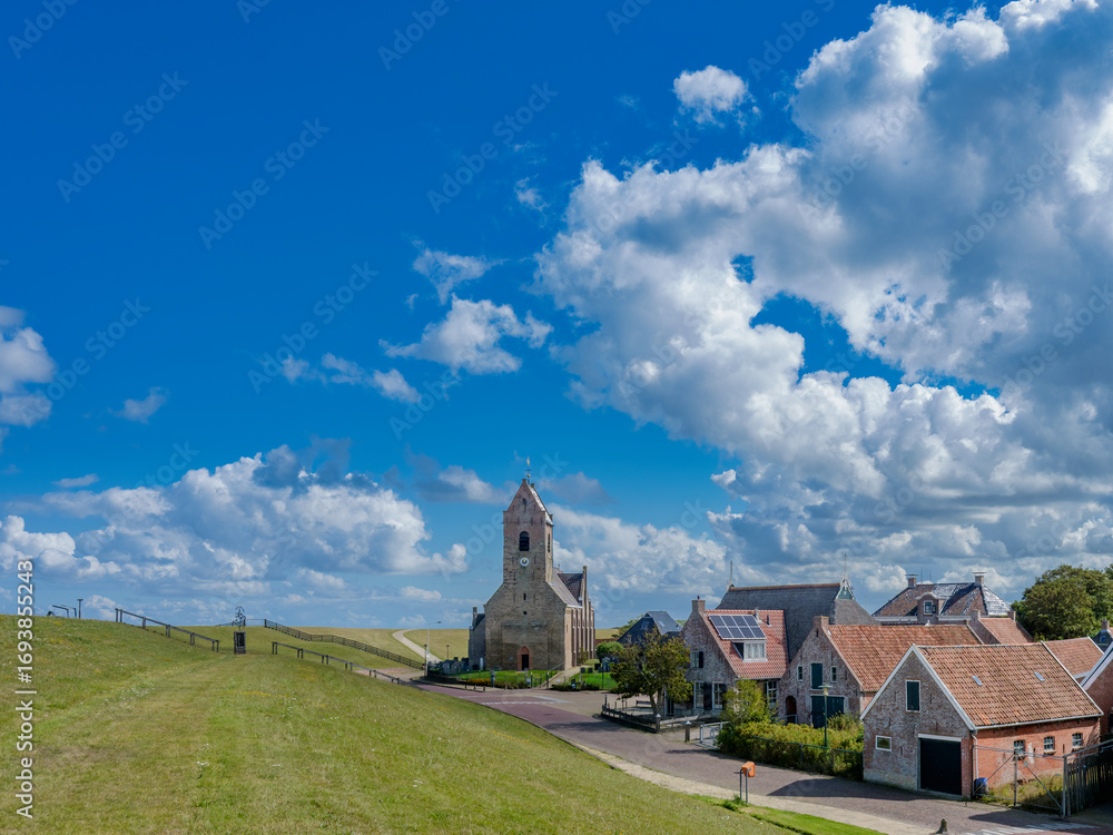 Fototapeta premium Village view with the Mariakerk with the Wadden Sea dike in Wierum, Friesland province, The Netherlands