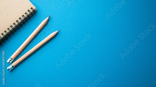 Two pencils and a notebook on a blue background