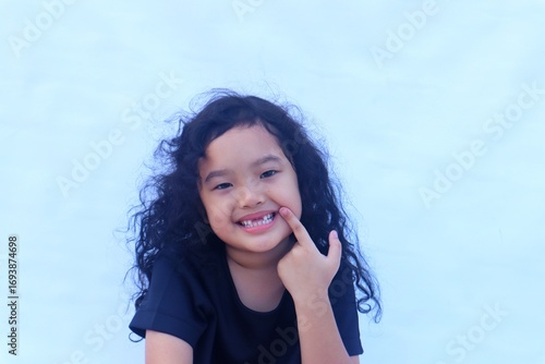Portrait of Asian girl with smiling face while showing her missing teeth.