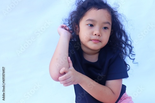 Asian girl scratches her elbow because it itches.