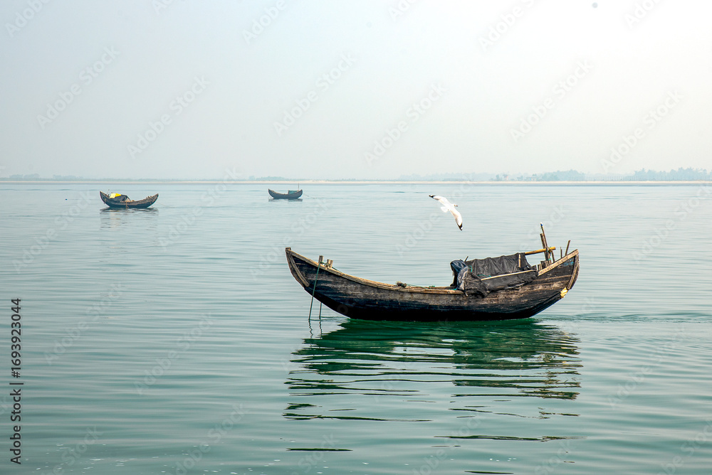 Naklejka premium Traditional Wooden Boats Sailing on Calm Lake Under Clear Sky
