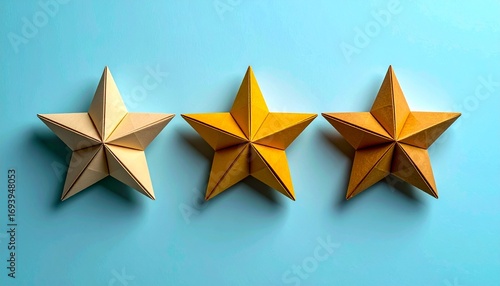 Three golden origami stars on a light blue background, artistic composition.