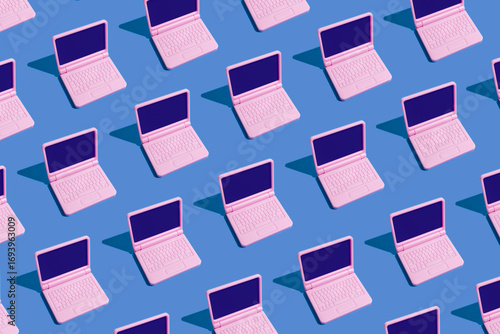 Pink laptops arranged in a seamless pattern on blue background
