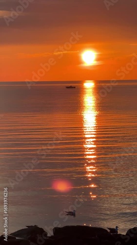 Sunset sky reflecting in the Baltic sea, view from the sandy shore in Sweden.
