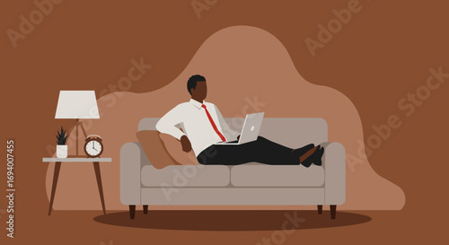Professional African American man works remotely from the comfort of his home, using a laptop while relaxing on a sofa. Represents modern work-life balance and flexible employment.