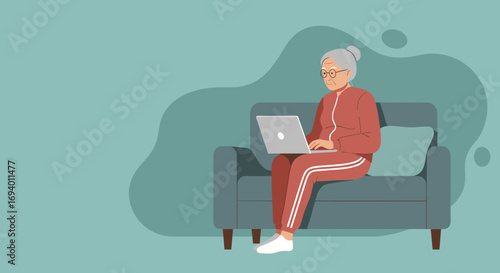 Elderly woman in a tracksuit comfortably using a laptop on a sofa at home, representing senior technology adoption, modern living, and digital literacy.