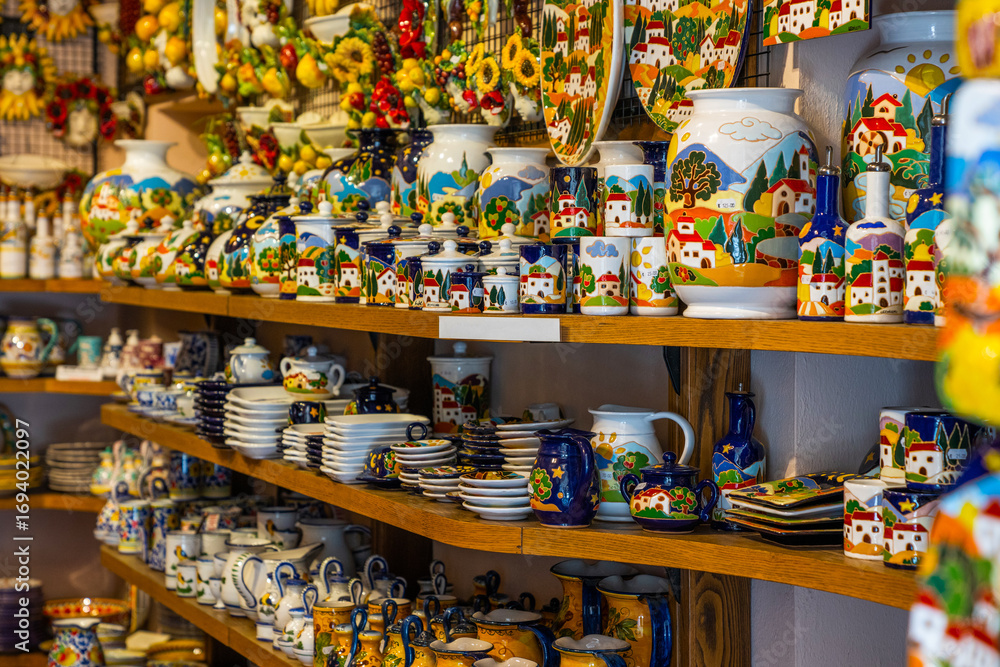 Naklejka premium Typical souvenirs in a shop in historic village San Gimignano, Tuscany, Italy. Detail of a local shop in the streets. Traditional souvenirs of ceramics. Europe tourism or vacation travel concept.