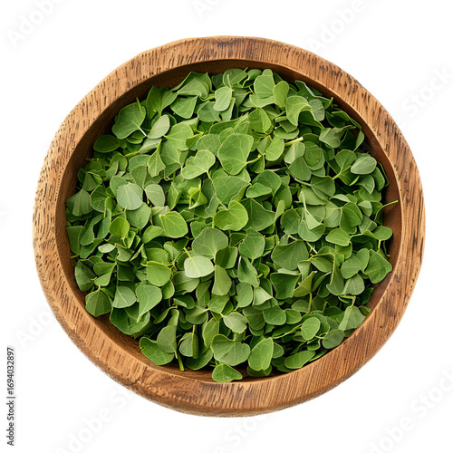 Wooden bowl filled with fresh green moringa leaves