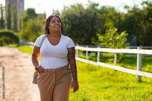 Plus size female with tattoo arm enjoying walk along pathway
