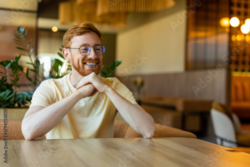 Photos Ginger bearded man in casual outfit seated indoors smiling warmly