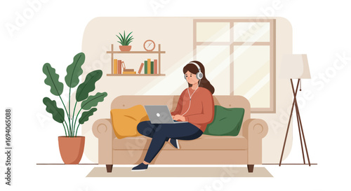 Young woman wearing headphones working on laptop while sitting on sofa.