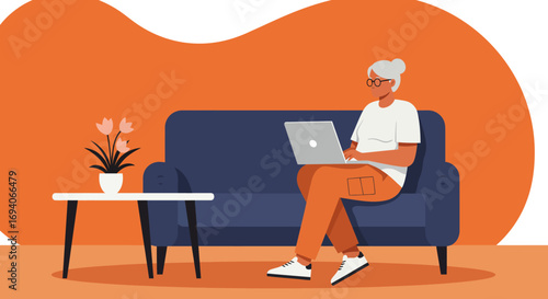 Mature woman engaging with technology, working remotely on her laptop from the comfort of her modern living room sofa, showcasing a connected senior lifestyle.
