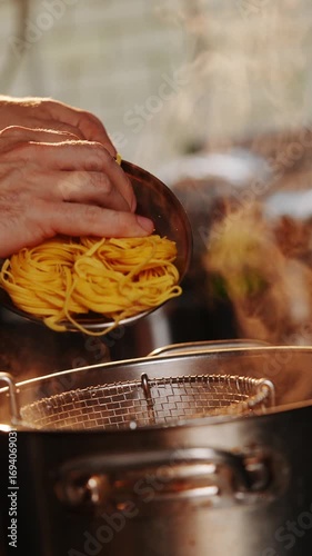 A person is cooking noodles in a pan with steam coming out of it. 