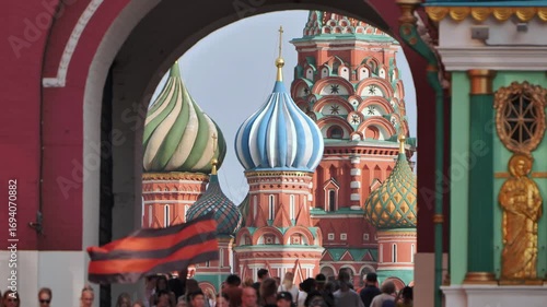 Saint Basil's Cathedral framed by Resurrection Gate with waving Ribbon of Saint George in Moscow.