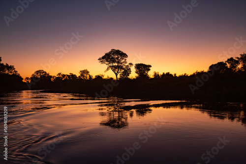 Breathtaking landscape of the Pantanal at dusk, with silhouettes of trees reflected on the water. Corumba, Mato Grosso do Sul, Brazil. Brazilian nature and wilderness.