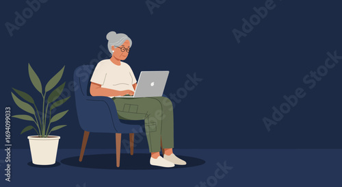 Elderly woman with glasses focused on her laptop in a comfortable armchair. Represents digital literacy, remote work, or modern retirement.