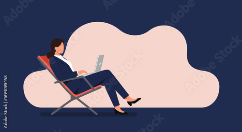 Professional woman in a suit works on her laptop while relaxing in a lounge chair, embodying flexible remote work or a digital nomad lifestyle.